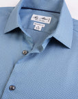 Close-up of a blue checkered shirt collar with brand label on a light gray background