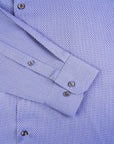 Close-up of a blue checkered shirt with rolled-up sleeves and button details.