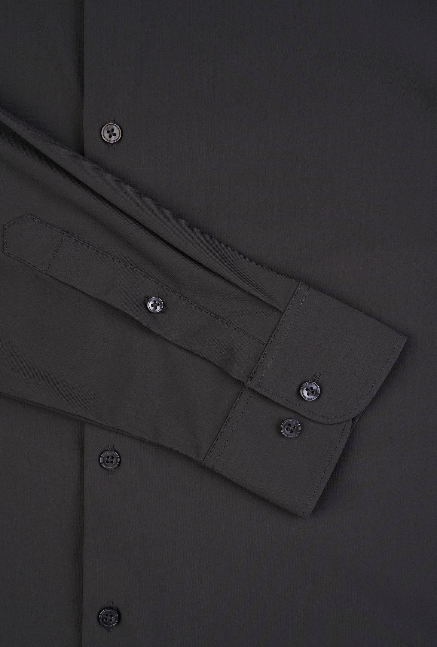 Close-up of a dark gray shirt with button details on a matching fabric background