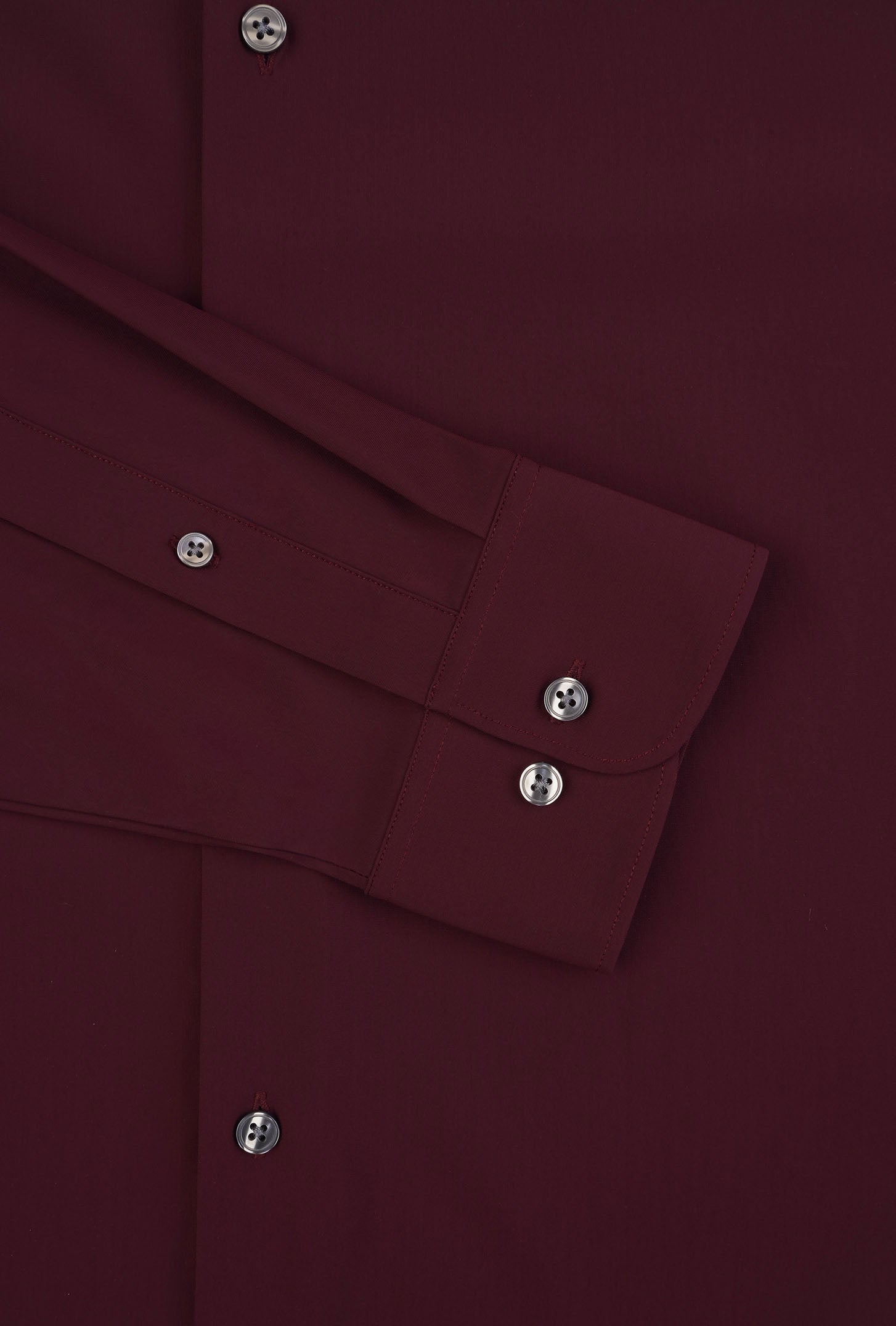 Close-up of a burgundy shirt with button details on a matching fabric background