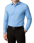 Man wearing a light blue dress shirt and black pants on a white background