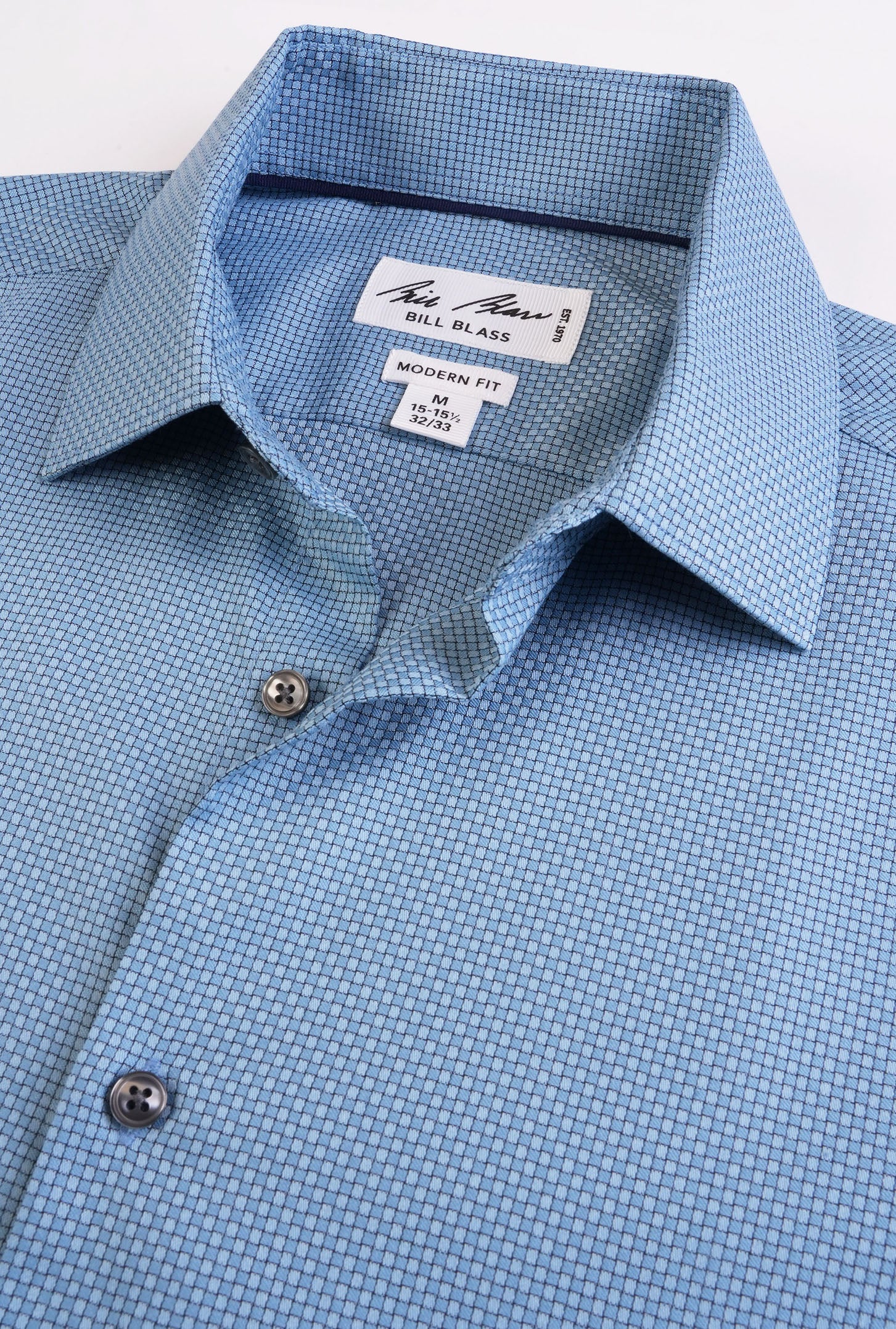 Close-up of a blue checkered shirt collar with brand label on a light gray background