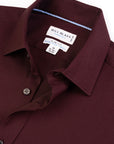 Close-up of a maroon shirt with a Bill Blass label on a white background