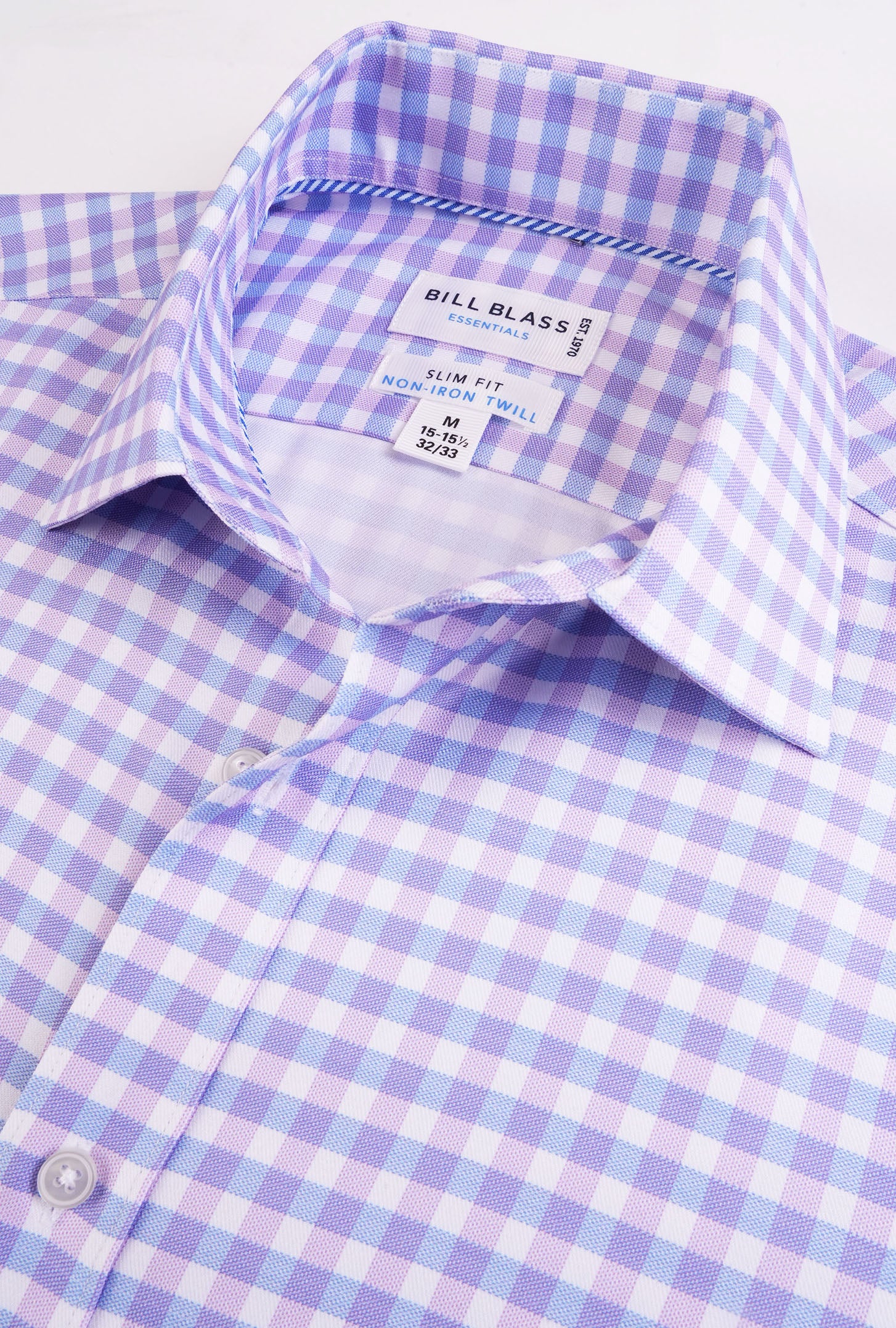 Close-up of a purple and white checkered shirt with 'Bill Blass' label.