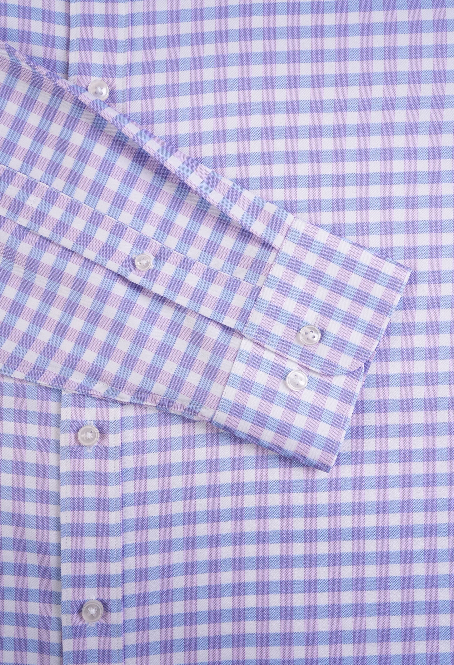 Close-up of a blue and white checkered shirt with rolled-up sleeve.